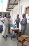 Dr. Kuyitila und der Biologie- und Chemielehrer vor der »naturwissenschaftlichen Sammlung« der Schule G.SCO.M.